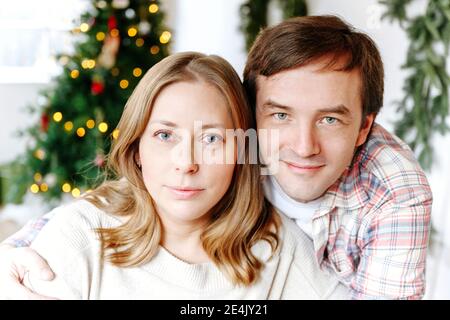 Gros plan d'un couple souriant avec arbre de Noël en arrière-plan à accueil Banque D'Images