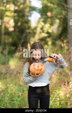 Surprise femme regardant la citrouille d'Halloween en se tenant au parc Banque D'Images