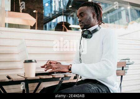 Homme d'affaires créatif avec une tasse à café jetable travaillant sur un ordinateur portable café Banque D'Images