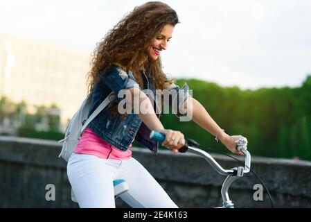 Belle jeune fille dans des vêtements décontractés de repos et de vélo dans l'été dans la ville le long du remblai Banque D'Images