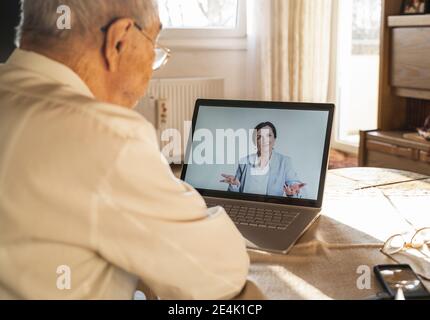 Femme médecin donnant des conseils à un patient masculin senior pendant la vidéo appelez à la maison Banque D'Images