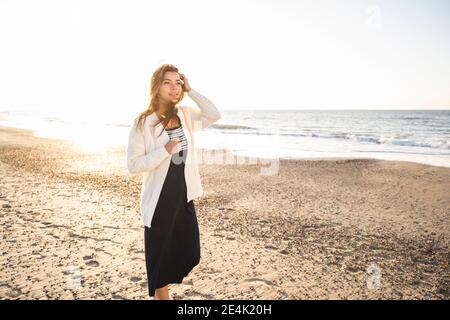 Jeune femme regardant loin en marchant à la plage sous le soleil jour Banque D'Images