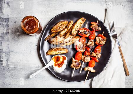 Brochettes de poulet Gyros avec tomates, poivrons, quartiers de pommes de terre et tzatziki sur la table Banque D'Images