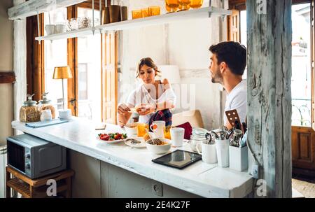 Jeune couple assis à table et prenant le petit déjeuner à la maison Banque D'Images