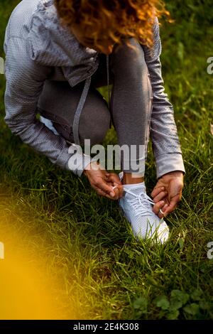 Athlète féminine qui noue des lacets tout en se caroutant au parc Banque D'Images