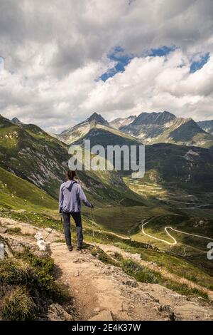 Femme avec un chien debout dans le paysage, regardant le col de montagne Banque D'Images