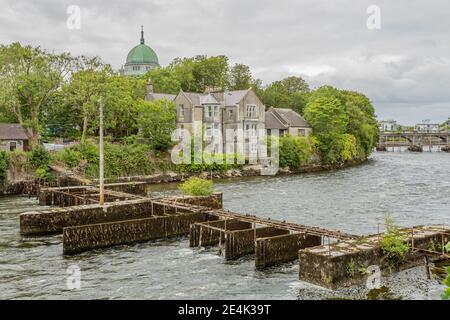 Rivière Corrib (canal d'Eglinton) avec eau courante avec le saumon Weir avec le dôme vert de la cathédrale en arrière-plan, Waterways of Galway, clo Banque D'Images