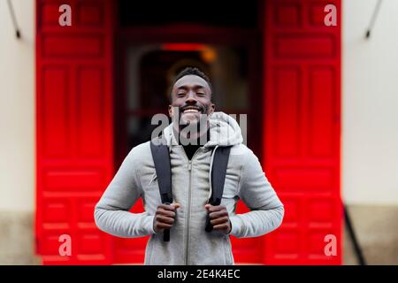 Jeune homme avec sac à dos souriant en plein air Banque D'Images