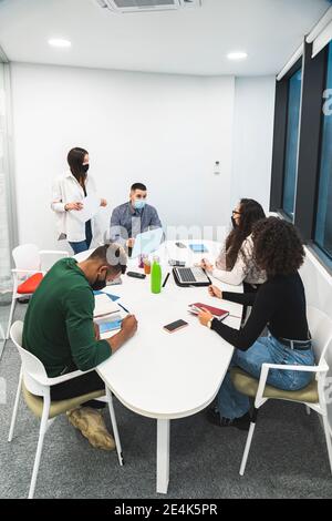 Des collègues créatifs, hommes et femmes, discutent lorsqu'ils sont assis à bord chambre au bureau Banque D'Images