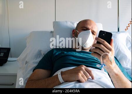 Patient avec un masque facial de protection reposant sur le lit à l'hôpital Banque D'Images