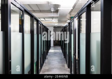 Long couloir avec cloison de porte en verre dans un bureau moderne Banque D'Images