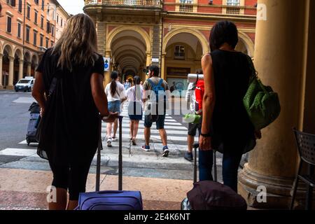 Touristes traversant la route dans le centre historique de la ville de Bologne avec des valises, le nord de l'Italie, l'Europe Banque D'Images