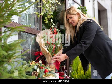 Fleuriste organisant des décorations de Noël à l'extérieur de la boutique de fleurs Banque D'Images