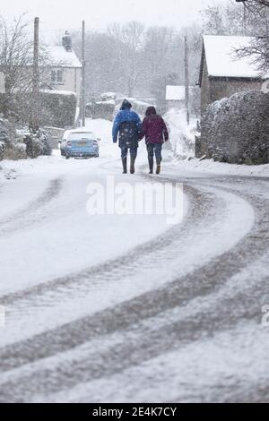 Flintshire, pays de Galles du Nord, Royaume-Uni mercredi 24 janvier 2021, Royaume-Uni Météo : fortes chutes de neige dans le Nord du pays de Galles avec un avertissement météorologique met Office en place neige comme une piste météo vers l'est à travers le pays. Un couple dans le village de Lixwm bravant la chute de neige lourde qui est prévue pour la journée dans la région de Flintshire © DGDImages/Alamy Live News Banque D'Images