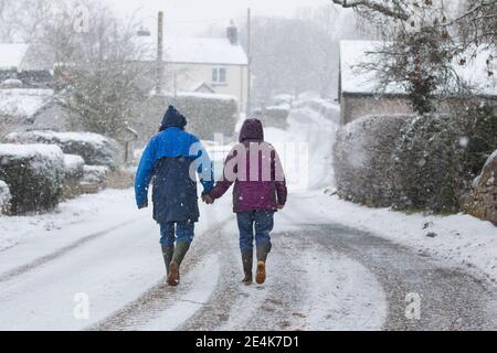 Flintshire, pays de Galles du Nord, Royaume-Uni mercredi 24 janvier 2021, Royaume-Uni Météo : fortes chutes de neige dans le Nord du pays de Galles avec un avertissement météorologique met Office en place neige comme une piste météo vers l'est à travers le pays. Un couple dans le village de Lixwm bravant la chute de neige lourde qui est prévue pour la journée dans la région de Flintshire © DGDImages/Alamy Live News Banque D'Images