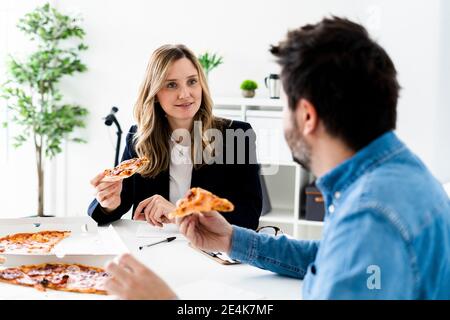 Les gens d'affaires mangent de la pizza et parlent au bureau pendant la pause Banque D'Images