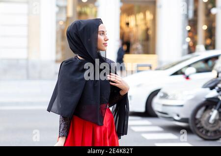 Portrait de la jeune belle femme portant le hijab noir posant au milieu de rue Banque D'Images