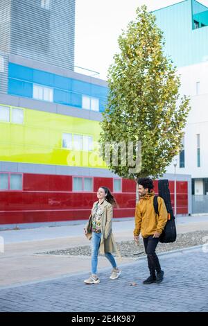 Homme transportant de la guitare tout en marchant avec la femme sur le sentier dans ville Banque D'Images