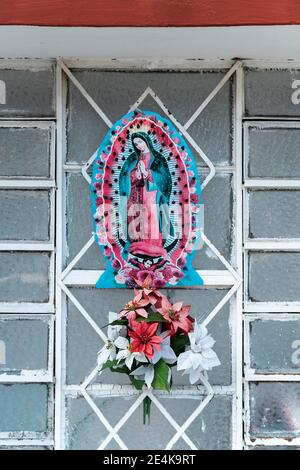 Figurine Virgin Mary avec fleurs sur grille métallique Banque D'Images