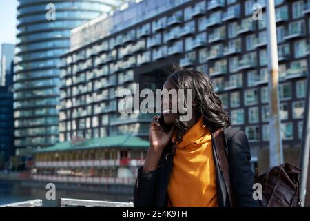 Femme d'affaires souriante parlant au téléphone en ville sous le soleil jour Banque D'Images