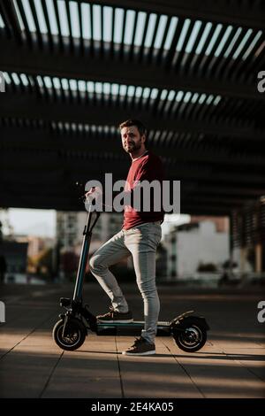 Homme debout avec un scooter électrique sur le sentier de la ville Banque D'Images