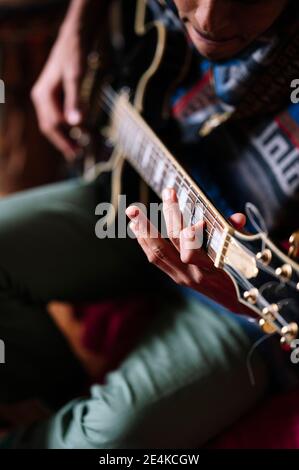 Afro musicien masculin pratiquant la guitare à la maison Banque D'Images