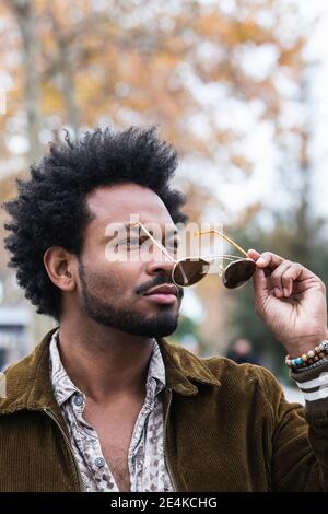 Gros plan de l'homme élégant avec des cheveux afro portant des lunettes de soleil Banque D'Images