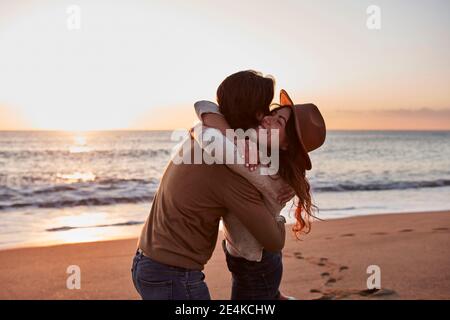 Un jeune couple s'embrasse les uns les autres en se tenant à la plage Banque D'Images