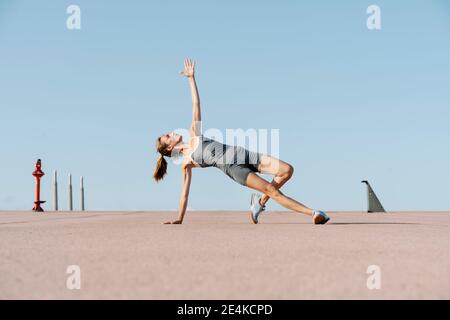 Sportswoman faisant de l'exercice de yoga avec la main levée tout en équilibrant d'un côté Banque D'Images