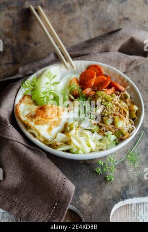 Bol de nouilles soba avec chou, carottes, chou-rave, œuf frit et herbes Banque D'Images