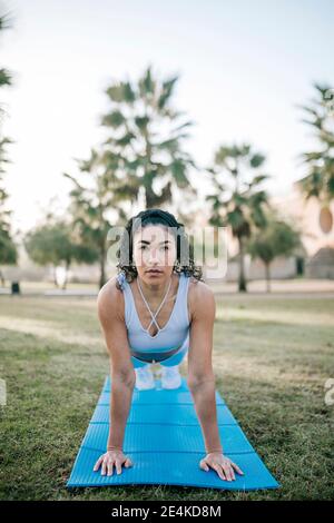 Sportswoman faisant pousser sur tapis d'exercice dans le parc public Banque D'Images