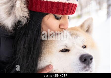 Affectueuse femme adulte de taille moyenne embrassant chien pendant l'hiver Banque D'Images