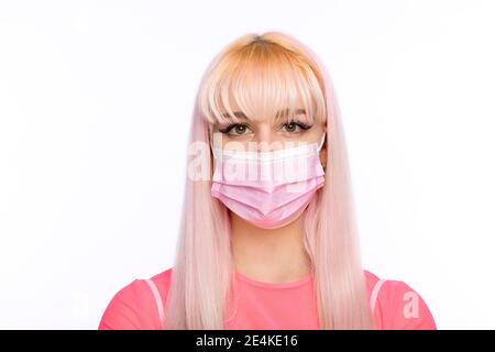 Belle jeune femme avec des blonds portant un masque de visage pendant pandémie Banque D'Images