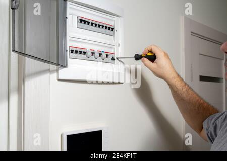 Un gros plan d'un ingénieur électricien travaillant dans un panneau électrique d'alimentation dans un immeuble d'appartements. Vérifier les paramètres de la centrale électrique. Banque D'Images