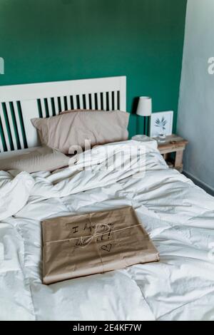 Cadeau emballé dans du papier brun sur le lit à la maison Banque D'Images