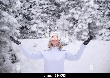 Femme âgée en tricot jouant avec la neige pendant les vacances Banque D'Images