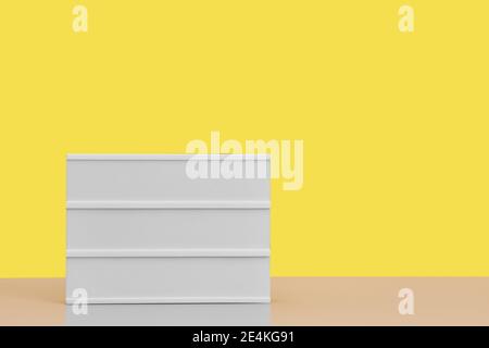 Image d'arrière-plan graphique d'un panneau blanc vierge sur la table contre un arrière-plan jaune vif, maquette, espace de copie Banque D'Images