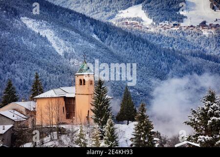 Vue sur l'église du village de Champagny-en-Vanoise avec brume et nuages autour Banque D'Images