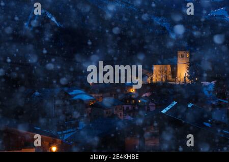 Vue nocturne de l'église du village de Champagny-en-Vanoise en France pendant fortes chutes de neige en hiver Banque D'Images