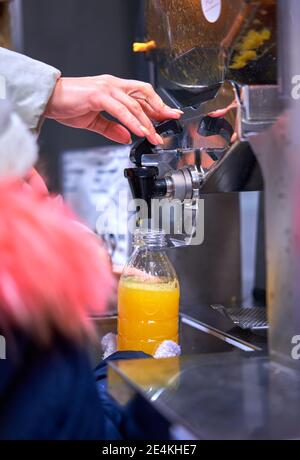 un enfant presse du jus d'orange dans un magasin Banque D'Images