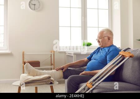 Homme mature avec jambe cassée en fonte reste à la maison et attend que sa fracture osseuse guérisse Banque D'Images