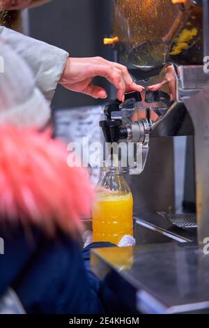 un enfant presse du jus d'orange dans un magasin Banque D'Images