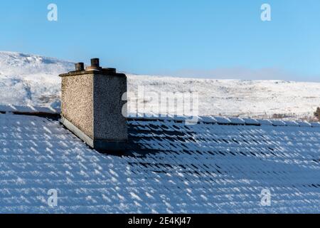 Couverture de neige blanc frais sur le toit de la maison et cheminée, fond ciel blanc, belle saison d'hiver au Royaume-Uni. Banque D'Images