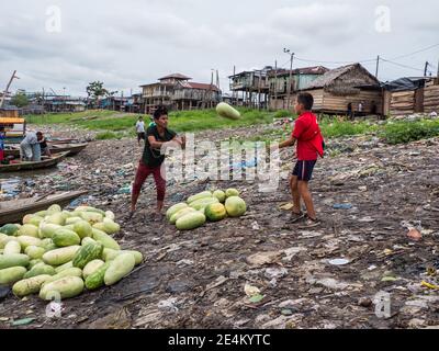Iquitos, Pérou - septembre 2019 : les hommes déplacent les fruits d'un bateau. On peut observer une pollution énorme en arrière-plan sur les rives de la rivière Itaya. Bas A Banque D'Images