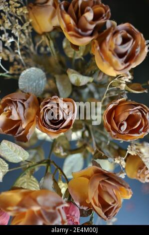 Vue de dessus de gros plan de roses artificielles de couleur brun d'automne sur fond noir. Verticale Banque D'Images