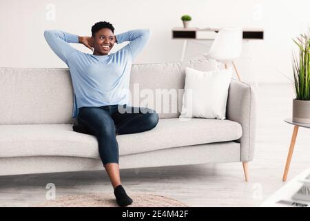 Femme noire ayant le repos à la maison sur le canapé Banque D'Images