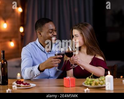 Dîner romantique. Joyeux couple multiracial célébrant ensemble la Saint-Valentin, Drinking Red Wine Banque D'Images