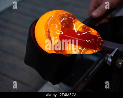 Le souffleur de verre utilise une forme en bois humide pour façonner le verre rouge fondu à l'extrémité du tuyau de soufflage de verre. Atelier traditionnel de verre tchèque fait main à Ku Banque D'Images