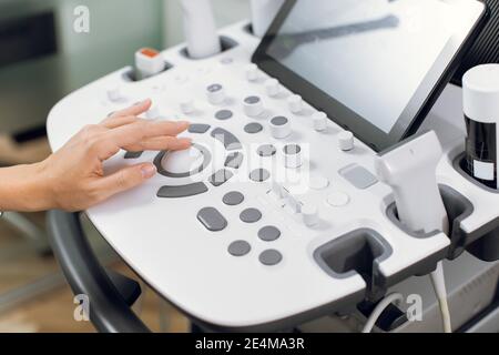 Gros plan sur un appareil médical moderne, un échographe au travail. Main d'une femme médecin échographiste professionnelle en appuyant sur les boutons Banque D'Images