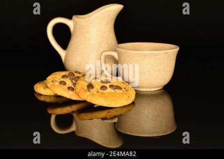 Trois biscuits entiers ronds, de couleur sable, parfumés et doux frais avec morceaux de chocolat au lait, se trouvent sur un fond noir. Banque D'Images